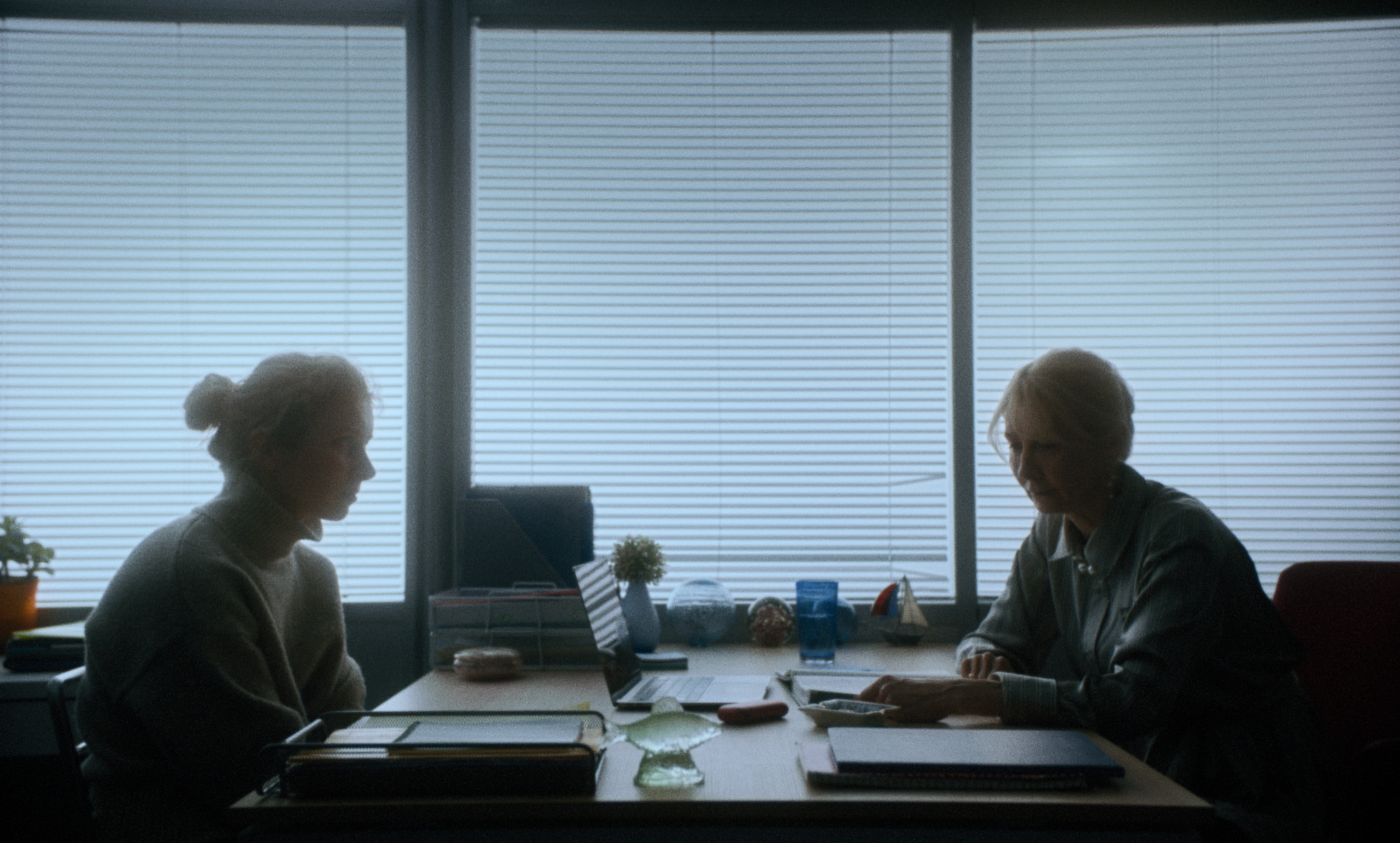 Women in an office throw papers in the air during a chaotic moment — a still from Kira’s Dream.