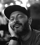 Bearded man in cap smiling, resting head, black and white photo.