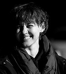 Black and white portrait of a smiling woman in a dark jacket.
