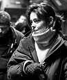 Sigourney Weaver bundled in a warm coat, scarf, and gloves, looking right.